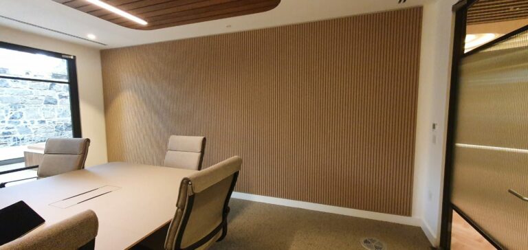 wooden wall panelling in a board room with a wooden table and brown chairs.