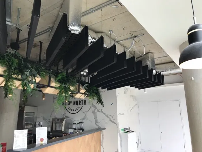 Black wavy acoustic fins hanging from the ceiling in a kitchen.