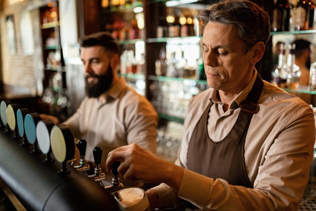 Mid,Adult,Bartender,And,His,Coworker,Working,In,A,Pub